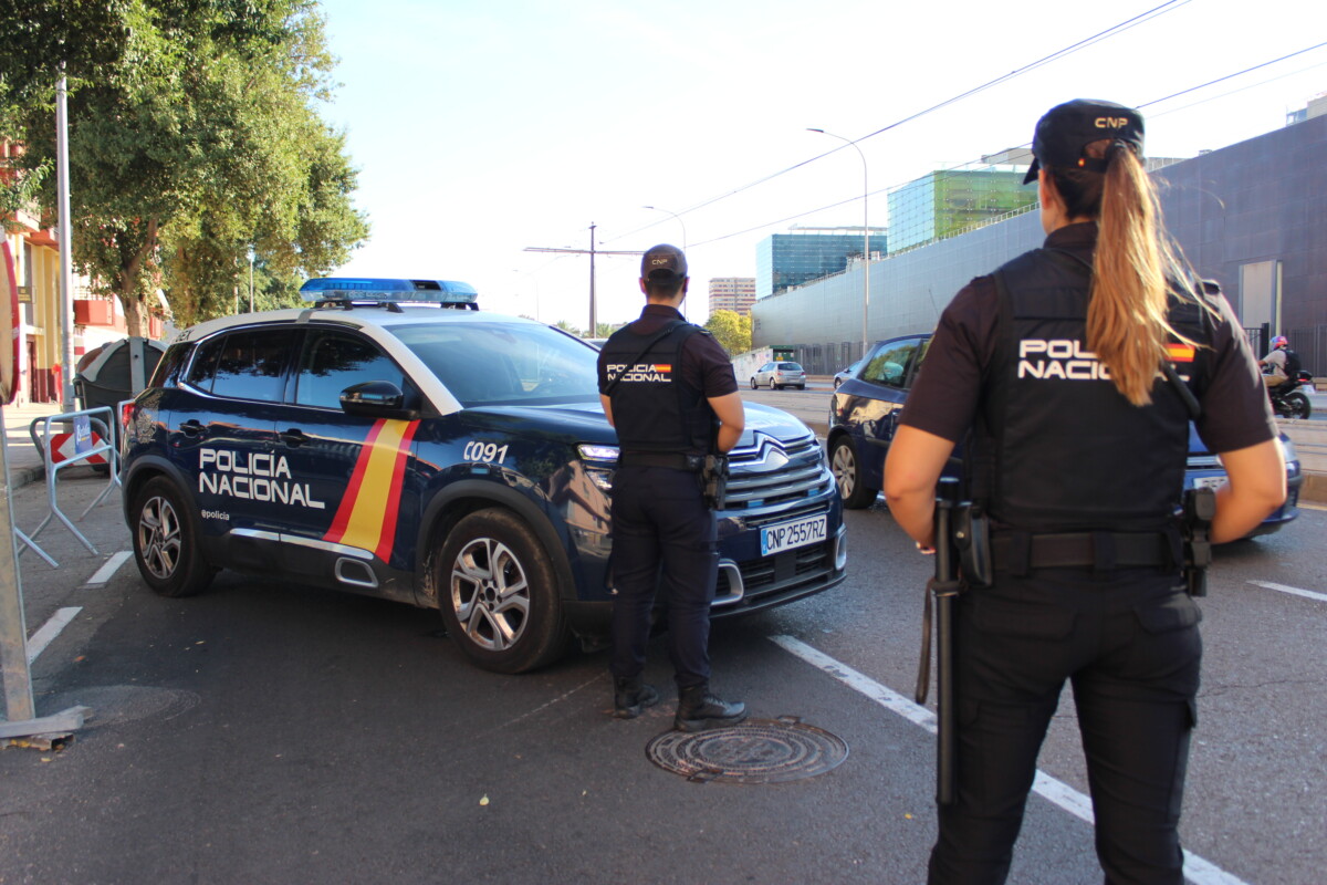Dos agentes de Policía Nacional junto a un coche patrulla